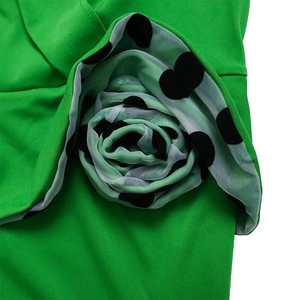 Gros plan sur une rose 3D en mousseline à pois noirs sur une robe de couleur vert vif