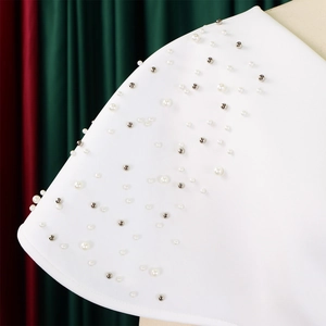 Detail van de V-hals jurk met witte parels en zilverkleurige klinknagels borduurwerk