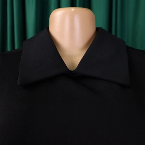 Détail de robe noire élégante montrant un col pointu classique et coutures nettes