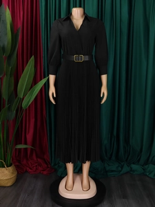 Detail of elegant black pleated dress showing refined fabric texture and golden buckle belt