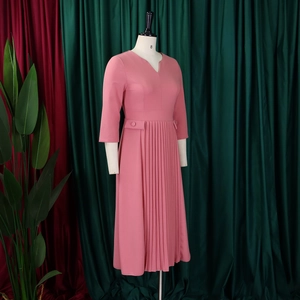 Detail of pink V-neck pleated dress featuring decorative waist buckle and tiered sleeves