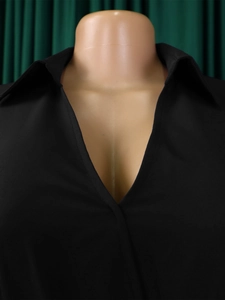 Detail of black long-sleeved dress featuring deep V-neckline and classic turnover collar