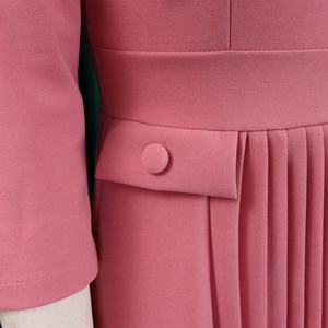 Detail of rose pink dress featuring elegant vertical pleats and a matching fabric button