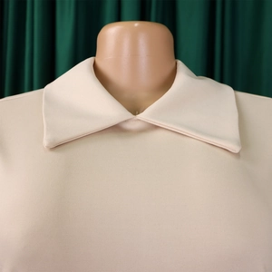 Gros plan sur le col polo beige élégant et la texture fine en maille de la robe