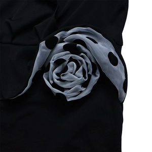 Detail of a 3D polka dot rose applique made of grey sheer fabric on a black dress