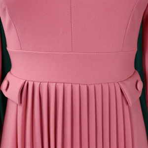 Detail of pink dress waist featuring pleated skirt with decorative buttons and pocket flaps