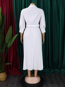 Detail of white pleated maxi dress with matching wide belt and elegant cuffed long sleeves