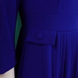 Detail of royal blue pleated dress featuring waist stitching and fabric-covered buttons