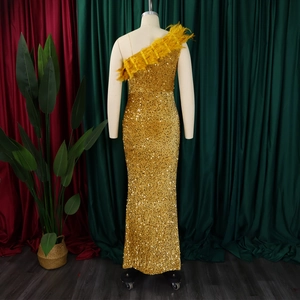 Detail eines goldenen Pailletten-Abendkleides mit elegantem Federbesatz am Schultergurt