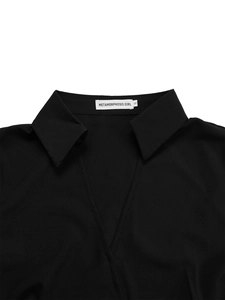 Close-up of elegant black V-neck collar with branded label on smooth pleated dress