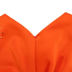 Detail van V-hals op oranje jurk met faux parel accenten en een onzichtbare rits