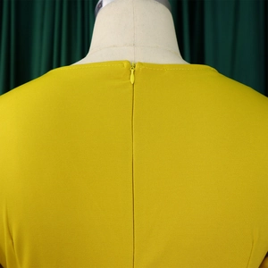Dettaglio posteriore di una tuta giallo senape con cerniera invisibile e trama a rete