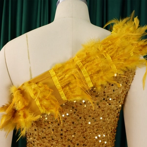 Detailaufnahme goldener Pailletten und gelber Federn an einem One-Shoulder-Abendkleid