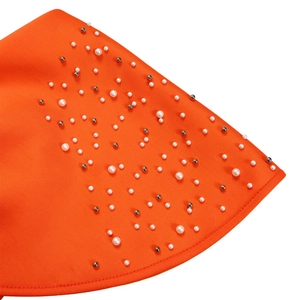 Detailopname van oranje jurkstof met witte faux-parels en zilverkleurige kralendetails