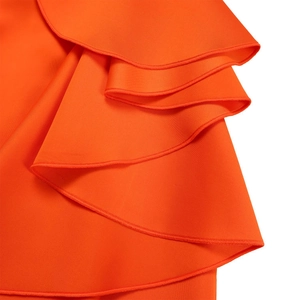 Detailopname van levendige oranje ruches en de zoomafwerking van een chique avondjurk