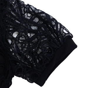 Close-up of intricate black floral lace pattern and pleated trim on a dress sleeve