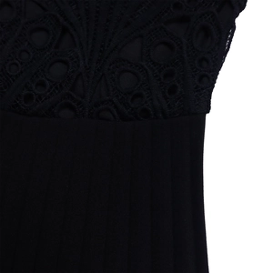 Close-up of intricate black floral lace patchwork and pleated fabric on an African dress