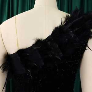 Nahaufnahme des schwarzen Pailletten-Abendkleids mit Federverzierung am One-Shoulder-Ausschnitt