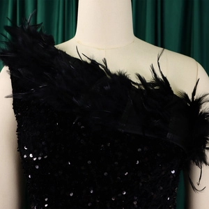 Nahaufnahme von schwarzen Pailletten und flauschigen Federn am One-Shoulder-Abendkleid