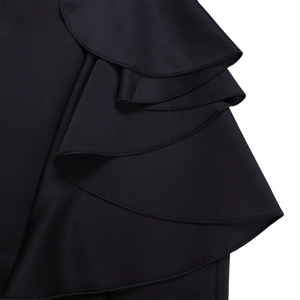 Gedetailleerde close-up van gelaagde ruches en fijne stiksels op een zwarte avondjurk