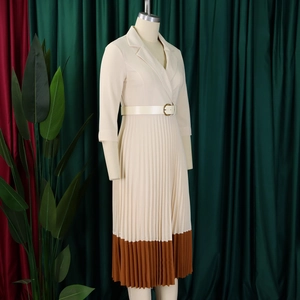 Détail de la robe plissée beige élégante avec ourlet caramel et ceinture à boucle blanche