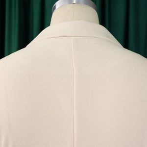 Détail du col du blazer beige et de la couture arrière de la robe de bureau ajustée