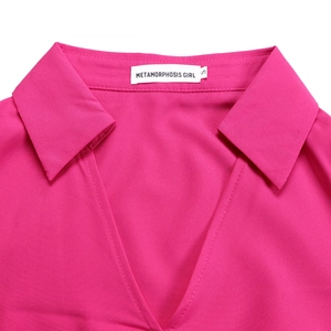 Detail of elegant fuchsia pleated dress showing classic collar and brand label