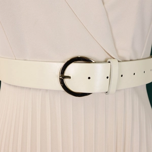 Détail d'une robe plissée crème avec fine ceinture en similicuir et boucle dorée ronde