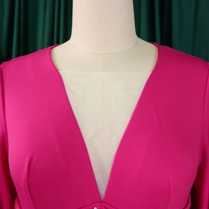 Dettaglio tuta rosa con profondo scollo a V e inserto in rete beige traslucida