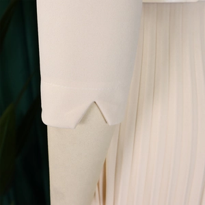 Détail du revers en V et du tissu plissé sur une élégante robe beige pour femmes