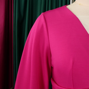 Dettaglio dello scollo a V e maniche a sbuffo su un tessuto di tuta rosa rossa