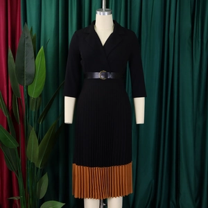 Détail d'une robe noire à revers avec boucle de ceinture et ourlet plissé marron