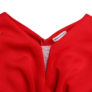Detail van een rode jurk met V-hals, verborgen ritssluiting en een zijden merklabel