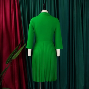 Detailweergave van smaragdgroene plisséjurk met chique revers en slank tailleontwerp