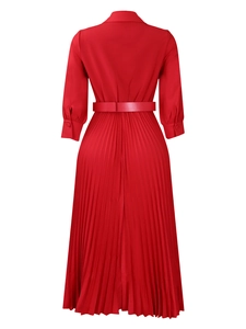 Detail view of the pleated hem and belted waist on a vibrant red long sleeve dress