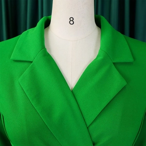 Detailweergave van grasgroene blazer met reverskraag en hoogwaardige getextureerde stof