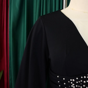 Dettaglio di una tuta con scollo a V e decorazioni di perle e strass in vita