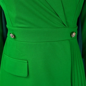 Detail van de smaragdgroene wikkeljurk met gouden reliëfknoppen en geplooide textuur