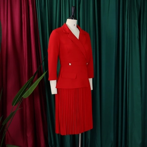 Detail van de geplooide textuur en taille van een rood zakelijk damespak-setje