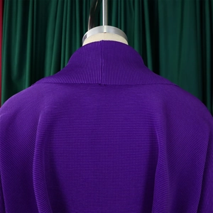 Dettaglio del top a collo alto viola scuro con pieghe orizzontali e trama a fisarmonica