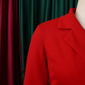 Detailopname van de rode blazer met inkeping in de revers en getextureerde stofafwerking