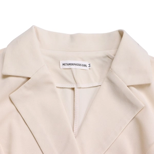 Détail du revers élégant et de l'étiquette de marque sur une robe business crème