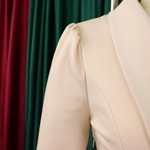 Close-up of elegant beige peplum top featuring pleated puff sleeves and a sharp lapel collar