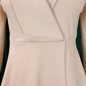 Macro shot of beige V-neck blouse with elegant ruffles and high-waisted twill fabric detail