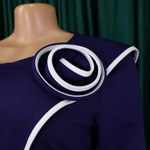 Detail of dark purple pencil dress with a 3D spiral flower and white contrast piping