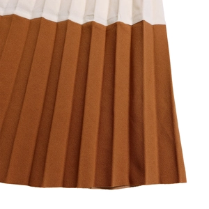 Détail d'une robe plissée bicolore avec un contraste élégant de blanc et d'ocre foncé
