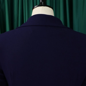 Detailopname van de halslijn en schouder van een donkerblauw jasje op een beige mannequin