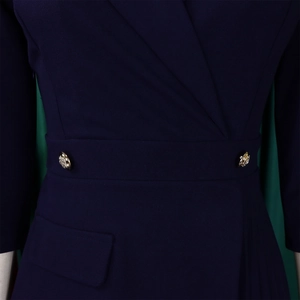 Detailweergave van donkerblauwe jurk met geplooide accenten en gouden knopen