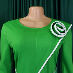 Close-up of emerald green dress with elegant white 3D spiral flower detail on the shoulder