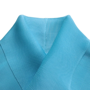 Dettaglio dell'elegante tessuto plissettato azzurro con trama fine e scollatura a V